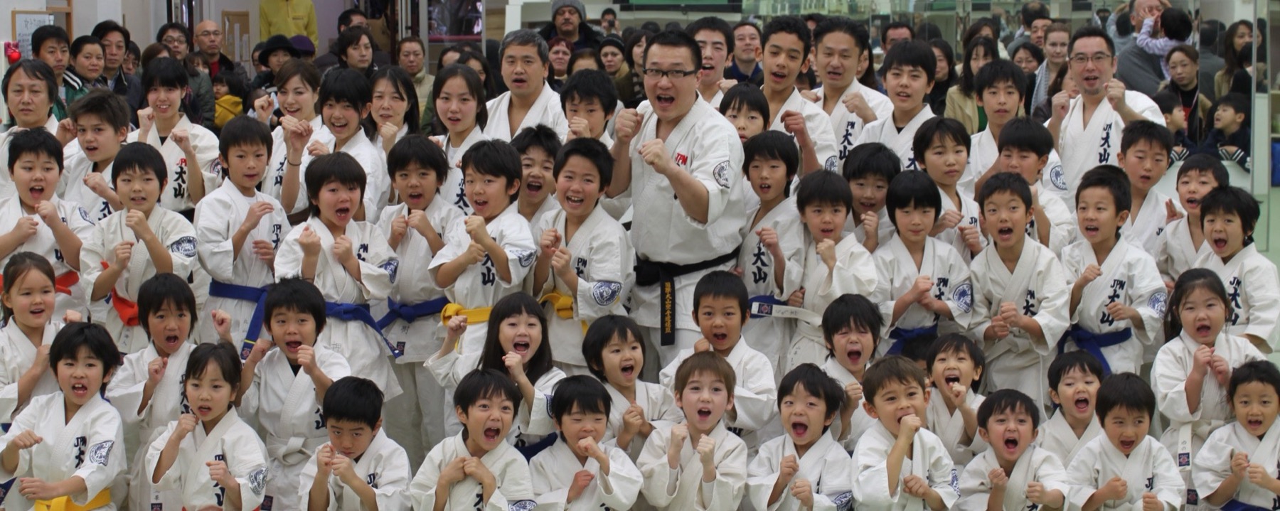 道場に集まった子どもたちと指導員が笑顔で拳を構えている集合写真
